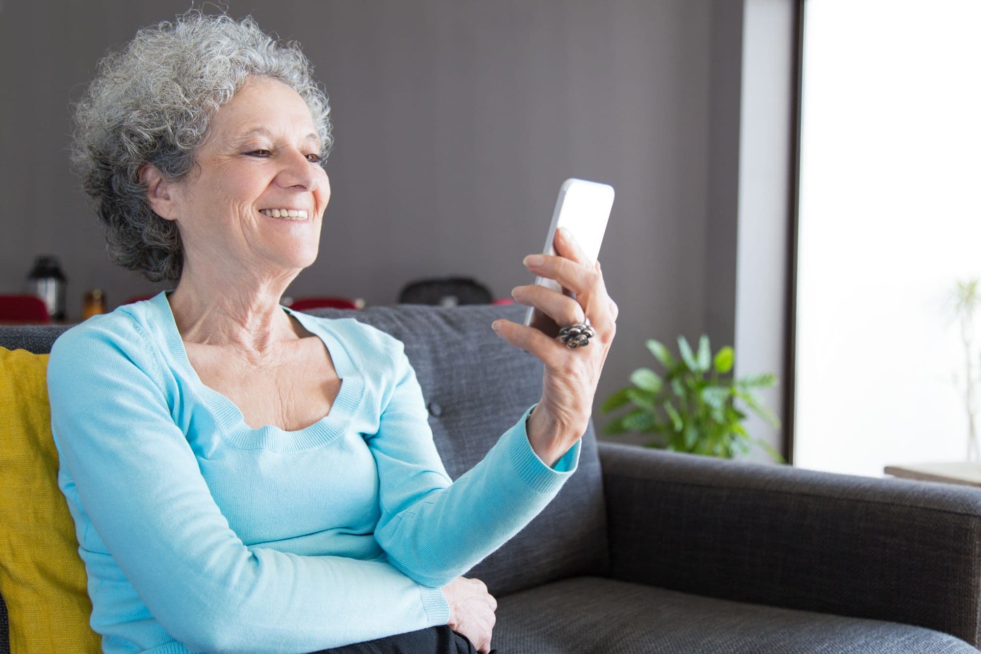 An older woman on a video call on her phone at home